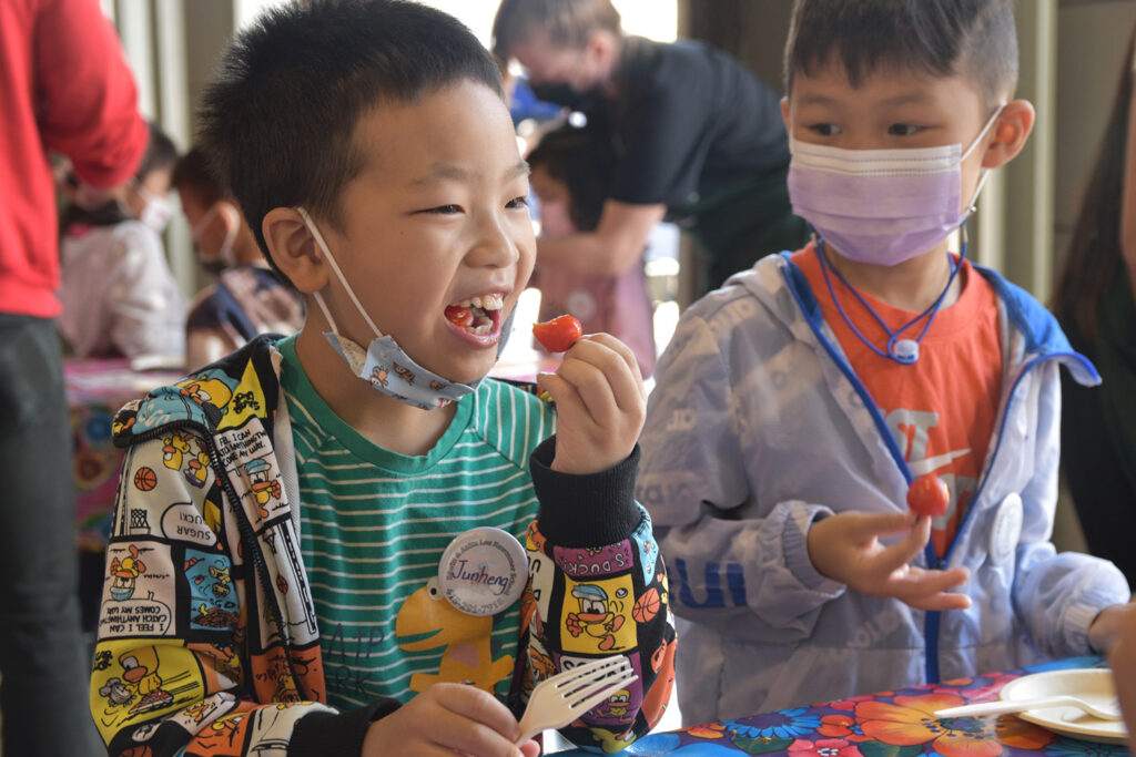 A Foodwise Kid eating a tomato and smiling