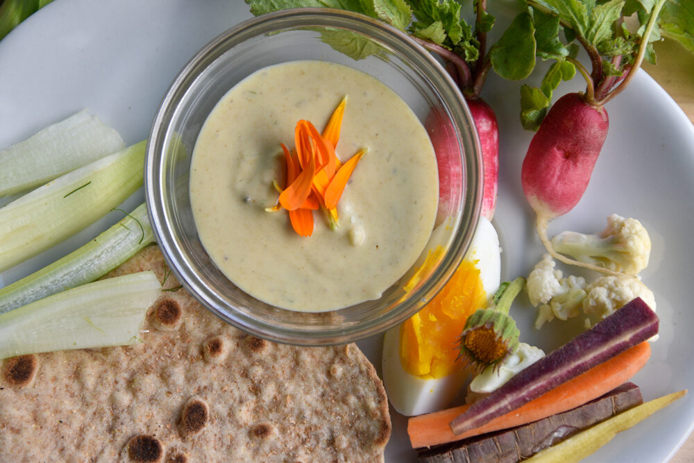 A dip with vegetables, bread, and a quartered egg on a platter