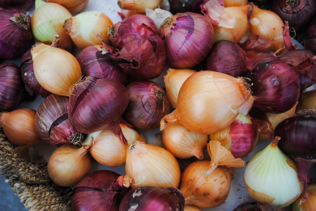 A mix of red, yellow, and white onions in a basket